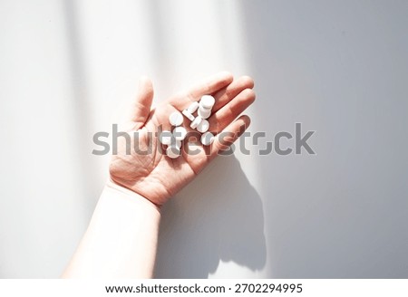 Assorted pills in a hand under diffused light. Aesthetic representation of healthcare and wellness.