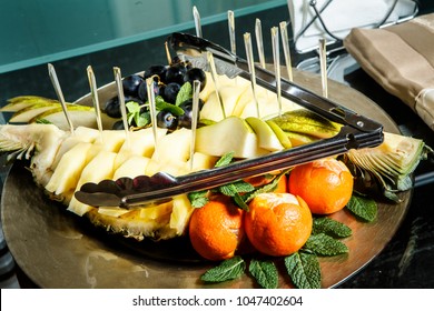 assorted pineapple, pear, grape, mandarins with skewers served on plate  - Shutterstock ID 1047402604