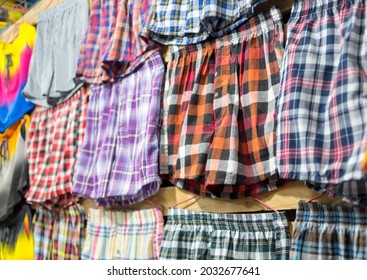 Assorted plaid boxer shorts hanging on a wall. Men's underwear for sale at a market stall or boutique.