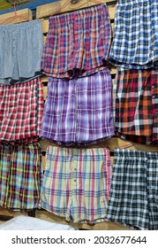 Assorted plaid boxer shorts hanging on a wall. Men's underwear for sale at a market stall or boutique.