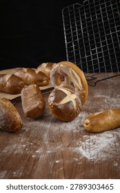 Assorted pretzels and lye bread rolls on a floured wooden table with a cooling rack and dark rustic background.