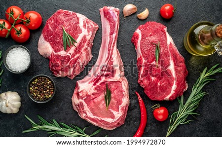 Assorted raw beef steaks. Tomahawk steak and ribeye steaks on stone background