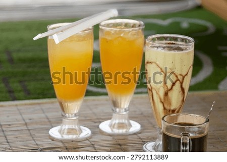  Assorted refreshing beverages including fresh orange juice glasses, avocado chocolate milkshake, and a hot cup of black coffee on a bamboo table.