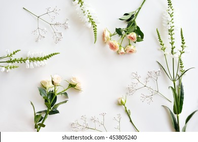 Assorted Roses Heads On White Background. Flowers And Leaves Scattered On A Table, Overhead View Wallpaper. Flat Lay, Top View.