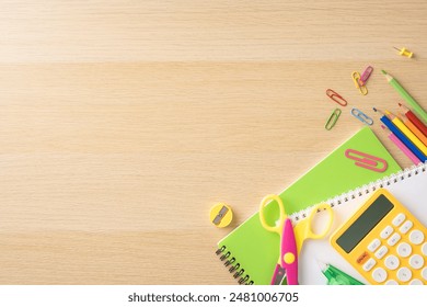Assorted school supplies including scissors, notebooks, and a calculator on a wooden desk, ideal for back to school