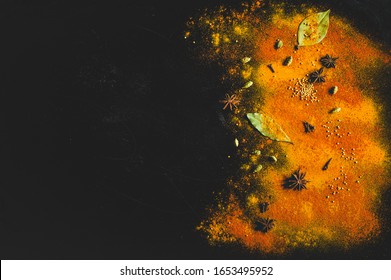 Assorted spices on dark black background. Seasonings for food. Space for text. Curry, paprika, pepper, cardamom, anise, cloves, bay leaf, turmeric. Top view. Close-up. Spices concept. Copy space