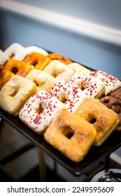 Assorted square-shaped donuts and sweets on trays in a light blue-colored room