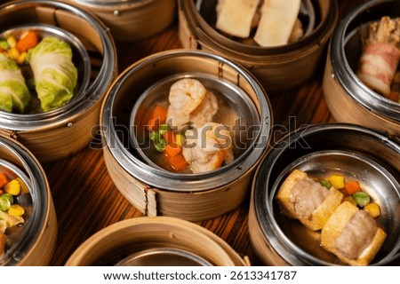 Assorted steamed dim sum with leaf garnish in traditional steamers.