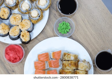 Assorted sushi and rolls set served on a dining table with chopsticks. Close up view of a varied sushi and rolls set beautifully arranged on a dining table. The composition includes traditional Japanese sides like soy sauce, ginger, and chopsticks, perfect for a lunch or dinner concept.