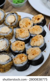 Assorted sushi and rolls set served on a dining table with chopsticks. Close up view of a varied sushi and rolls set beautifully arranged on a dining table. The composition includes traditional Japanese sides like soy sauce, ginger, and chopsticks, perfect for a lunch or dinner concept.