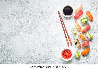 Assorted sushi set on white concrete background. Space for text. Japanese sushi, rolls, soy sauce, ginger, chopsticks. Top view. Sushi nigiri. Japanese dinner/lunch. Food frame. Different sushi mixed