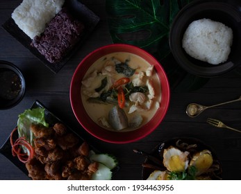 Assorted Thai Food Flatlay On Wooden Table. Thai Dishes Rustic Shot, Dark Food Photography Still Life. Green Curry, Glutinous Rice, And Fried Chicken.