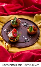 Assorted Three Bruschettes With Brioche Bun, Stuffed With Pepperoni, Prosciutto, Brie Cheese, Baked Tomatoes, Microgreen Pea Sprouts, Edible Violets And Spinach Leaves. The Bruschetta Is On A Brown Ce