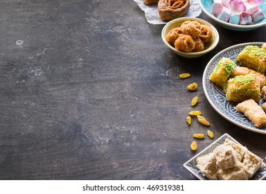 Assorted traditional eastern desserts on wooden background. Arabian sweets on wooden table. Baklava, halva, rahat lokum, sherbet, nuts, dates, kadayif on plates. Space for text. Selective focus