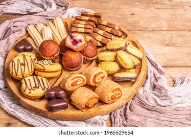 Assorted various cookies and muffins. Wooden combination plate on old boards table, close up