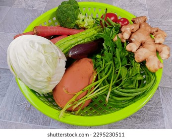 Assorted vegetable and fruit in a green basket.
