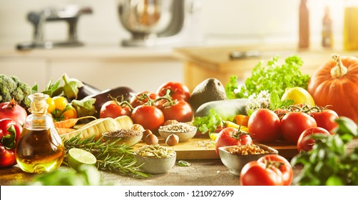 Assorted vegetables including large tomatoes and leafy greens sitting on cutting board with kitchen in background - Powered by Shutterstock