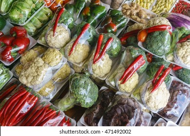 Assorted vegetables at market display wrapped with plastic sheet.