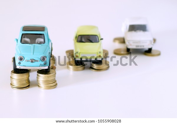 Assorted vintage collectible tiny cars,\
miniatures standing on stacks of golden coins. Image for\
transportation market, used retail and motor spares shop,\
automobile industry trend, car\
rental.