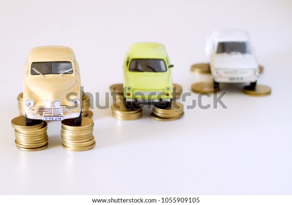 Assorted vintage collectible tiny cars,\
miniatures standing on stacks of golden coins. Image for\
transportation market, motor spares shop, automobile industry\
trend, car rental, and saving\
concept.