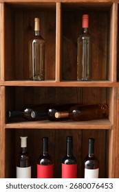 Assorted wine bottles displayed in rustic wooden wine rack for storage and presentation, the bottles are stored both upright and horizontally in the individual compartments of the wooden shelving unit