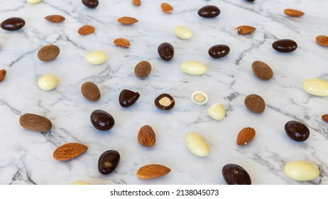 Assortment of almonds coated with chocolate scattered on a table. Mix of chocolate nut sweet snack. - Powered by Shutterstock