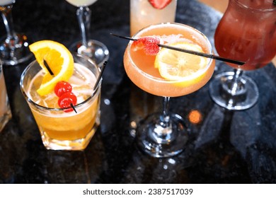 An assortment of beautifully garnished cocktails on a reflective bar surface, inviting a taste of varied flavors and a night of enjoyment - Powered by Shutterstock