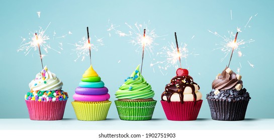 Assortment of brightly colored celebration cupcakes decorated with sparklers for a birthday party