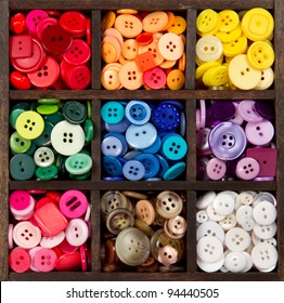 an assortment of buttons in a rainbow of colors, in a printers box
