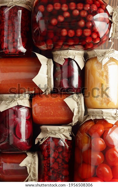 Assortment of canned vegetables and fruits- food\
in plastic free jars on wooden rustic table, flat lay, from above\
overhead top view, canned produce, saving leftovers food storage\
organization concept