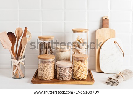 Assortment of cereals and pasta in glass jars and woden kitchen utensils. Zero waste idea