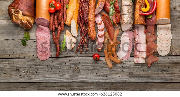 Assortment of cold meats, variety of processed\
cold meat products. On a wooden\
background