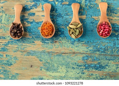 Assortment of colorful spices in the wooden spoons. Cloves, Saffron,  cardamom,  Pink peppercorns.  Food ingredients, top view, space for text - Powered by Shutterstock