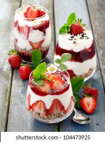 Assortment Of Creamy Gourmet Strawberry Desserts Layered In Decorative Patterns In Individual Glass Containers