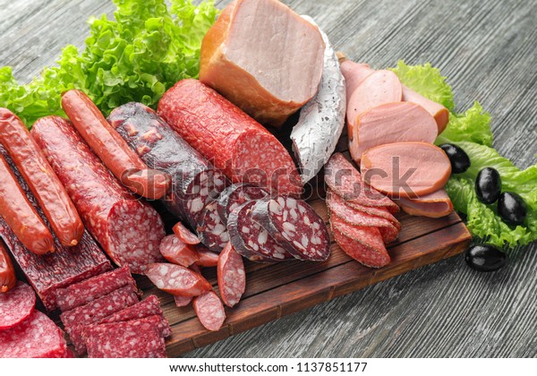 Assortment of\
delicious deli meats on wooden\
board
