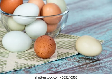 Assortment of different color, fresh chicken eggs in a glass bowl, vintage green background  