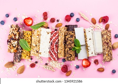 Assortment Of Different Granola Cereal Bars On Pink Background. Healthy Pre Or Post Workout Snacks With Fruits, Nuts And Berries. Copy Space. Top View