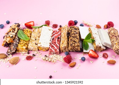 Assortment Of Different Granola Cereal Bars On Pink Background. Healthy Pre Or Post Workout Snacks With Fruits, Nuts And Berries. Copy Space. Top View