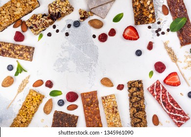 Assortment Of Different Granola Cereal Bars On White Stone Background. Healthy Pre Or Post Workout Snacks With Fruits, Nuts And Berries. Copy Space. Top View