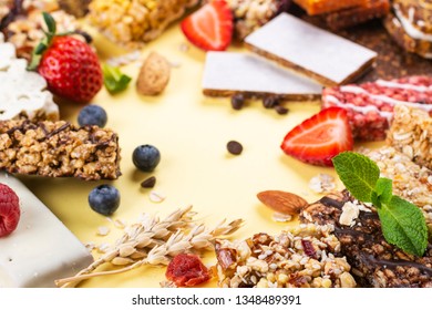 Assortment Of Different Granola Cereal Bars On Yellow Background. Healthy Pre Or Post Workout Snacks With Fruits, Nuts And Berries. Copy Space. Top View