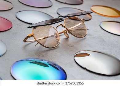 Assortment of different multicolored lenses for eyewear, fashion trendy sunglasses with changeable lenses lying on table in professional optical shop. Optician technician and eyesight concept 