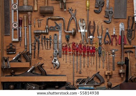 assortment of do it yourself tools hanging in a wooden cupboard against a wall