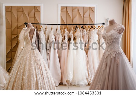 Assortment of dresses hanging on a hanger on the background studio. Fashion wedding trends. Interior of wedding shop.