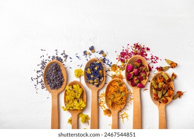 Assortment of dry herbal and berry tea in wooden spoons on a wooden background.Medicinal Healing herbs.Alternative medicine concept.Linden, calendula, cornflowers, marigold, tansy, tea rose.dry herbal