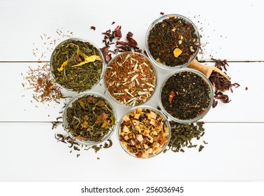 assortment of dry tea in glass bowls on wooden surface