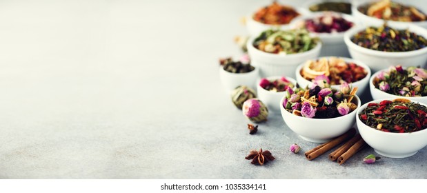 Assortment Of Dry Tea In White Bowls. Tea Backgound: Green, Black, Floral, Herbal, Mint, Melissa, Ginger, Apple, Rose, Lime Tree, Fruits, Orange, Hibiscus, Raspberry, Cornflower, Cranberry. Banner.