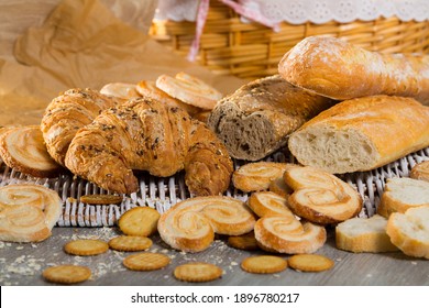 Assortment Of Fresh Baked Goods On Wicker Mat With Basket On Wooden Background