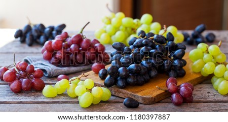 Assortment of fresh grape on cutting board. Grey wooden background.