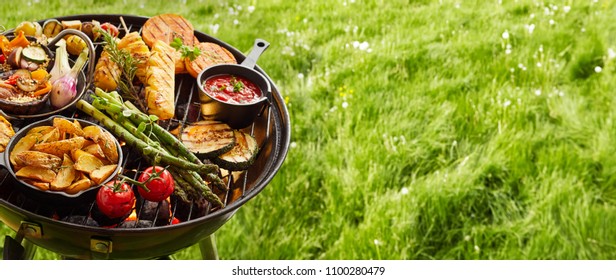 Assortment Of Fresh Healthy Vegetables On A BBQ Grilling Over A Hot Fire In A Green Grassy Spring Or Summer Field In Banner Format With Copy Space