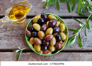 Assortment of fresh olives on a plate with olive tree brunches. Wooden background. Top view. - Powered by Shutterstock